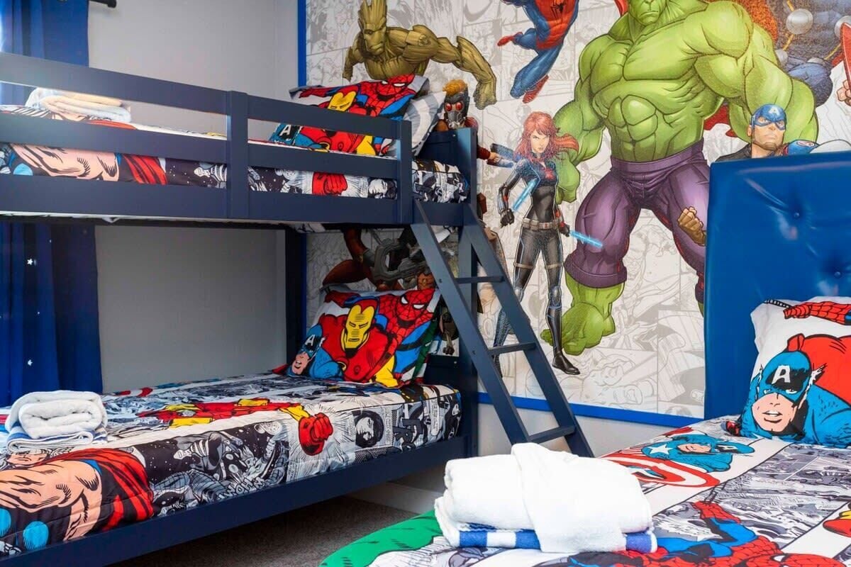 Un lit superposé avec une literie et des décorations murales sur le thème des super-héros.