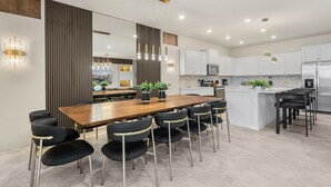 A modern kitchen with a central island, bar stools, and pendant lighting. - Ultimate 10 Bed Luxury Retreat With Epic Playroom (Clermont)