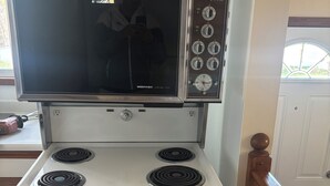 A kitchen with a stainless steel range hood, a microwave, and a built-in oven. - Monthly Rentals (Edmonton)