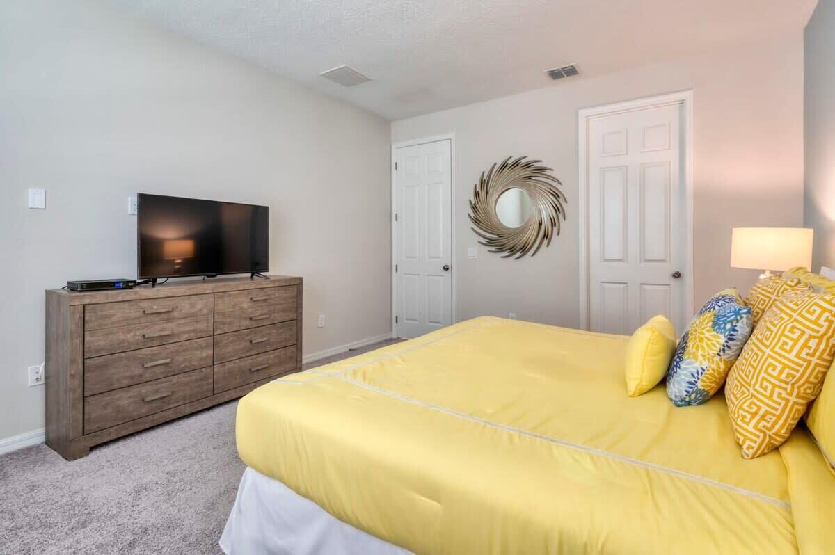 Un dormitorio con una cama grande, un aparador, un televisor y dos puertas.
