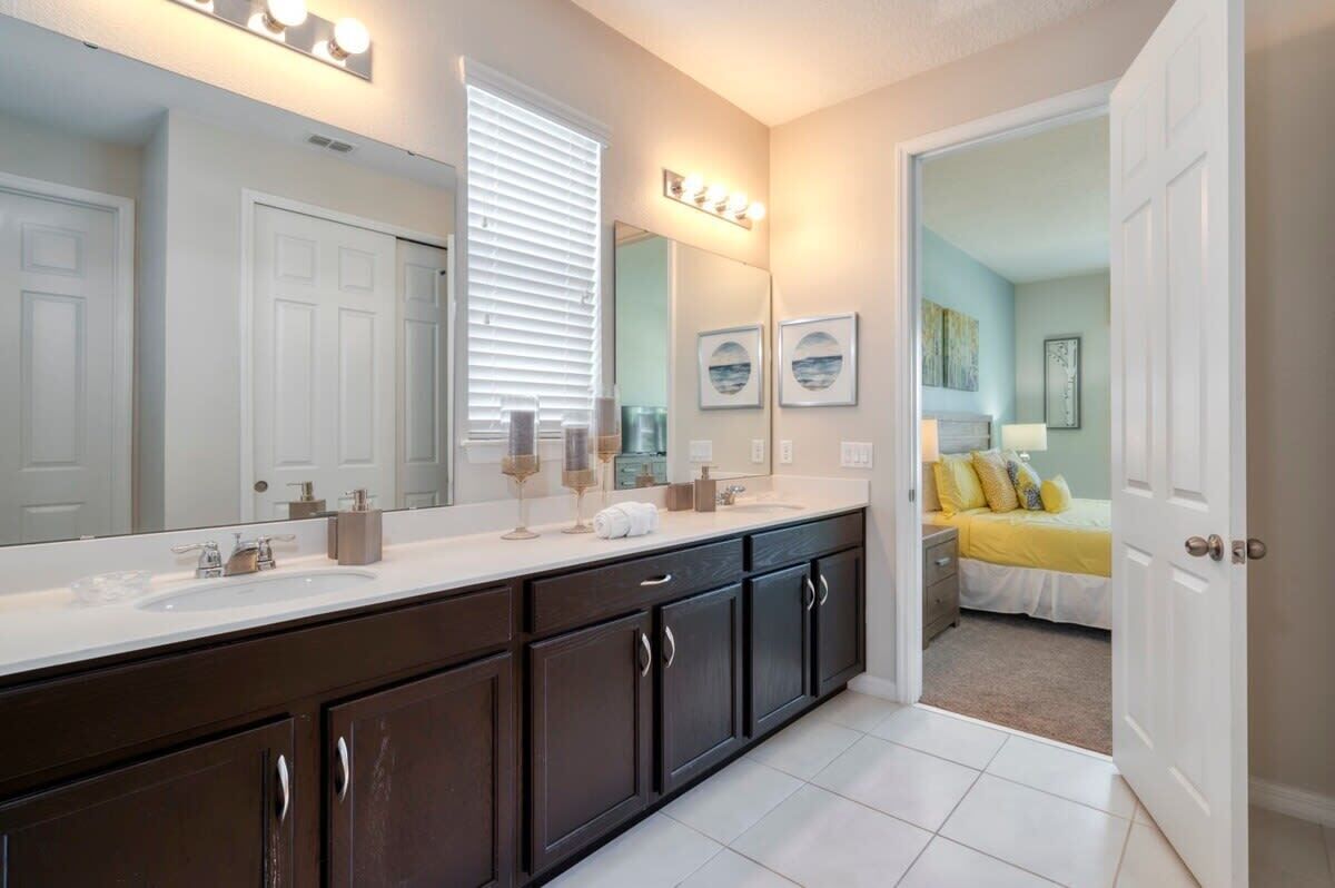 A modern bathroom with dark cabinetry, a large mirror, and a vanity with a sink.