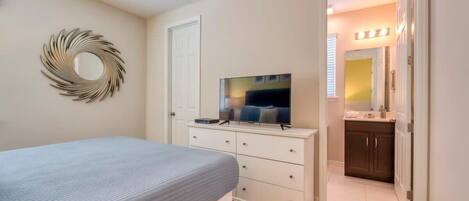 A bedroom with a bed, a dresser, a TV, and a mirror.