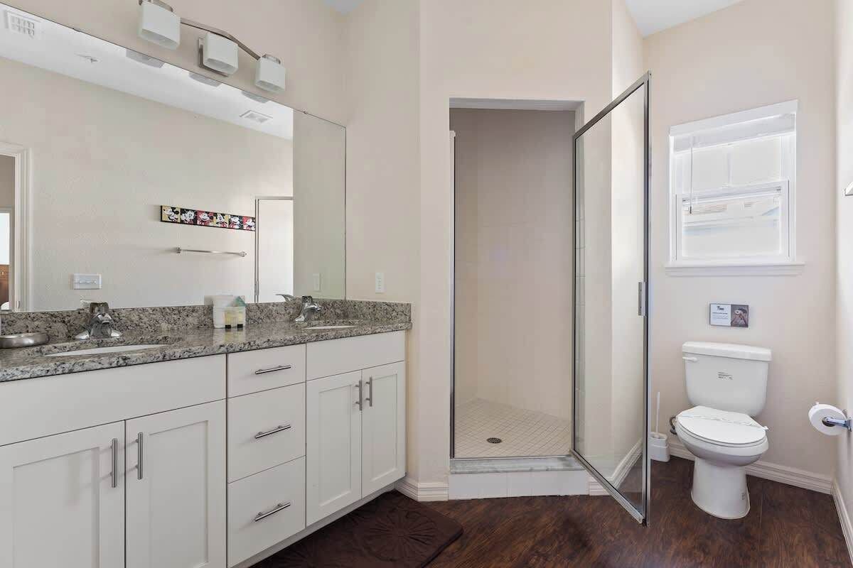 Een badkamer met douche, toilet en een grote spiegel.