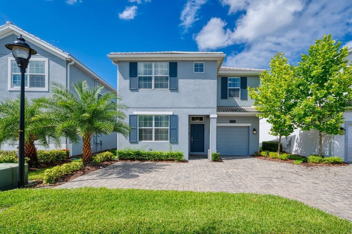 A two-story residential building with a garage, a well-maintained lawn, and a clear blue sky.