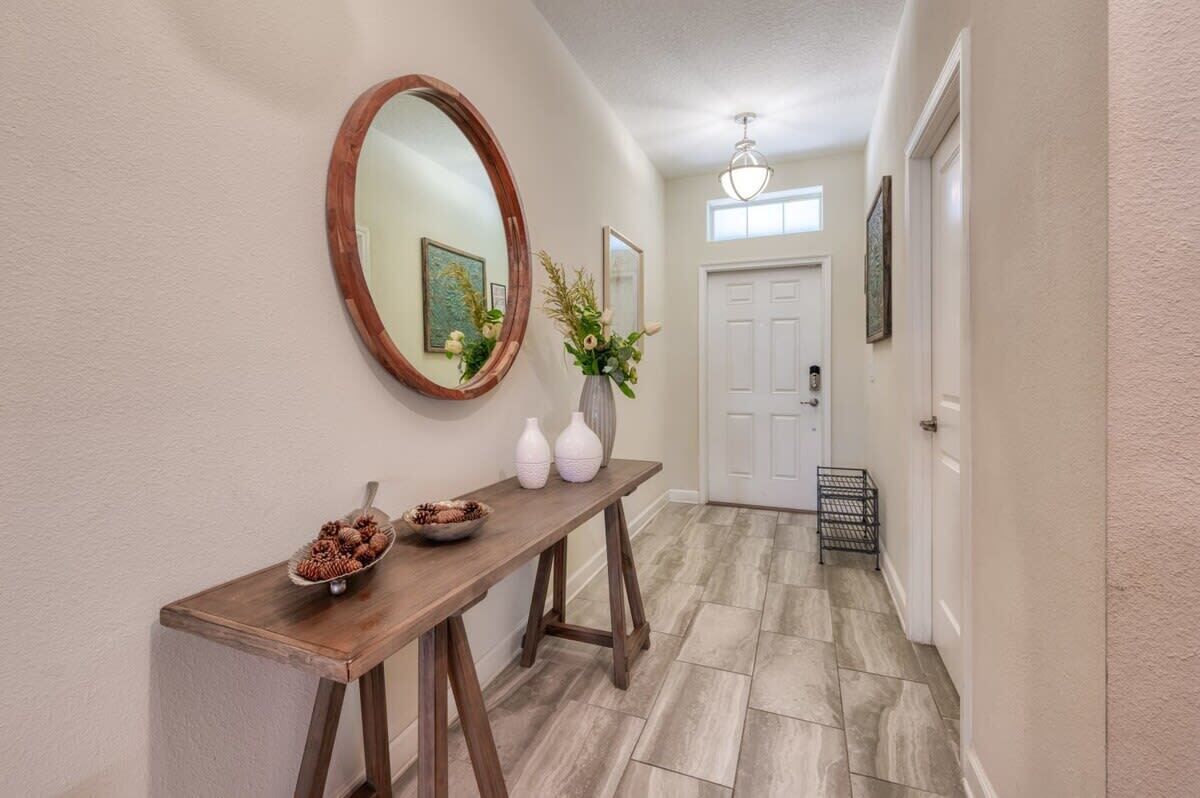 A hallway with a wooden console table, a mirror, and a vase with flowers.