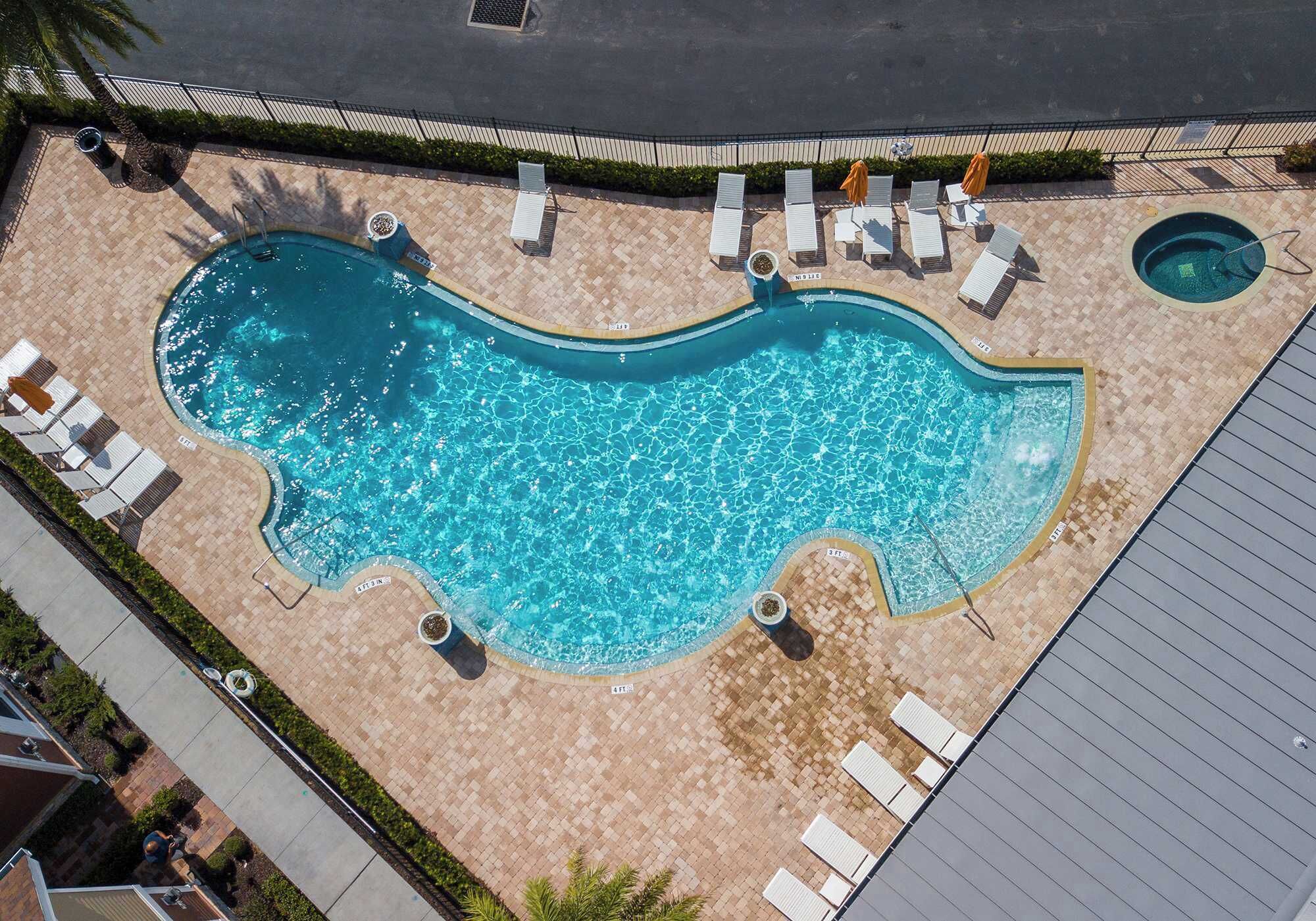 An aerial view of a swimming pool with sun loungers and a small hot tub.