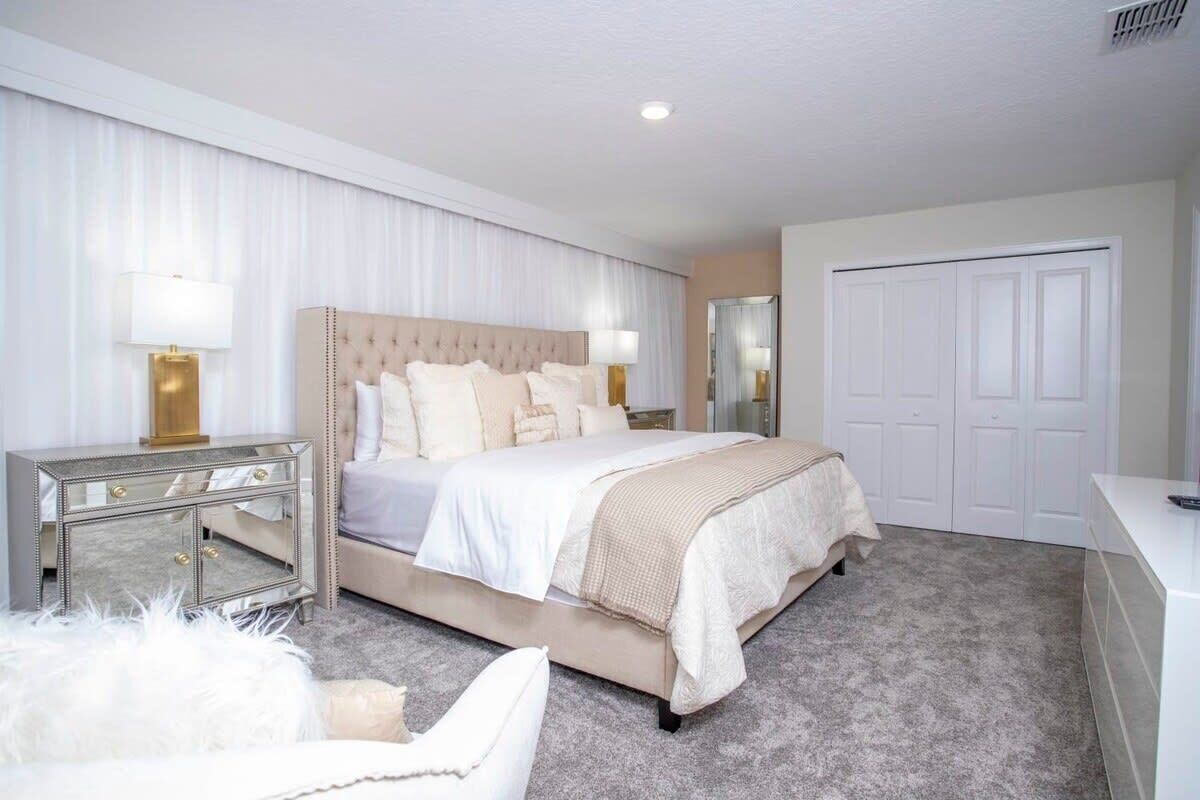A bedroom with a large bed, a nightstand, a mirror, and a wardrobe.