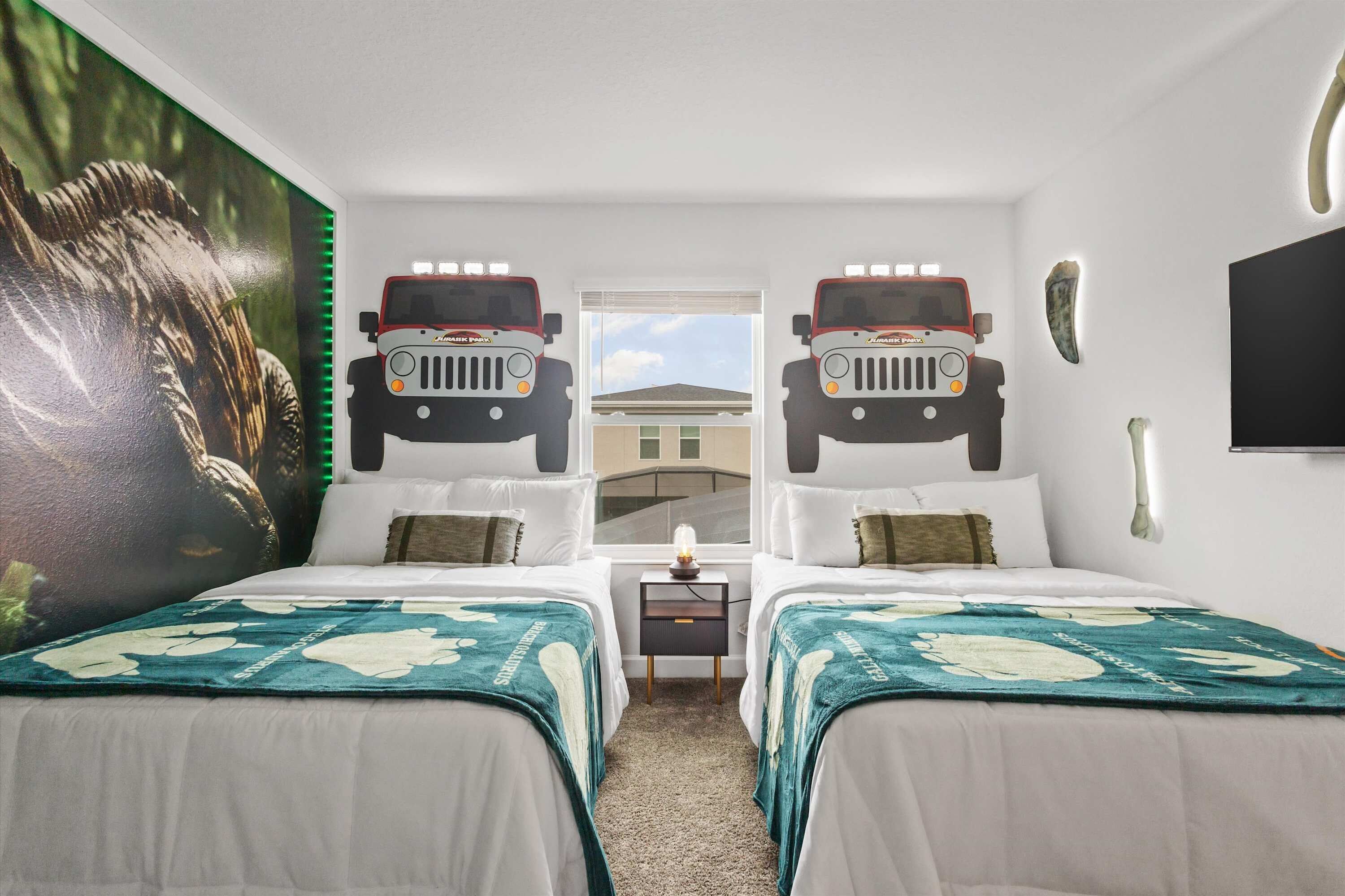 A hotel room with two beds, a large mural of a lion, and two Jeep Cherokees mounted on the wall.