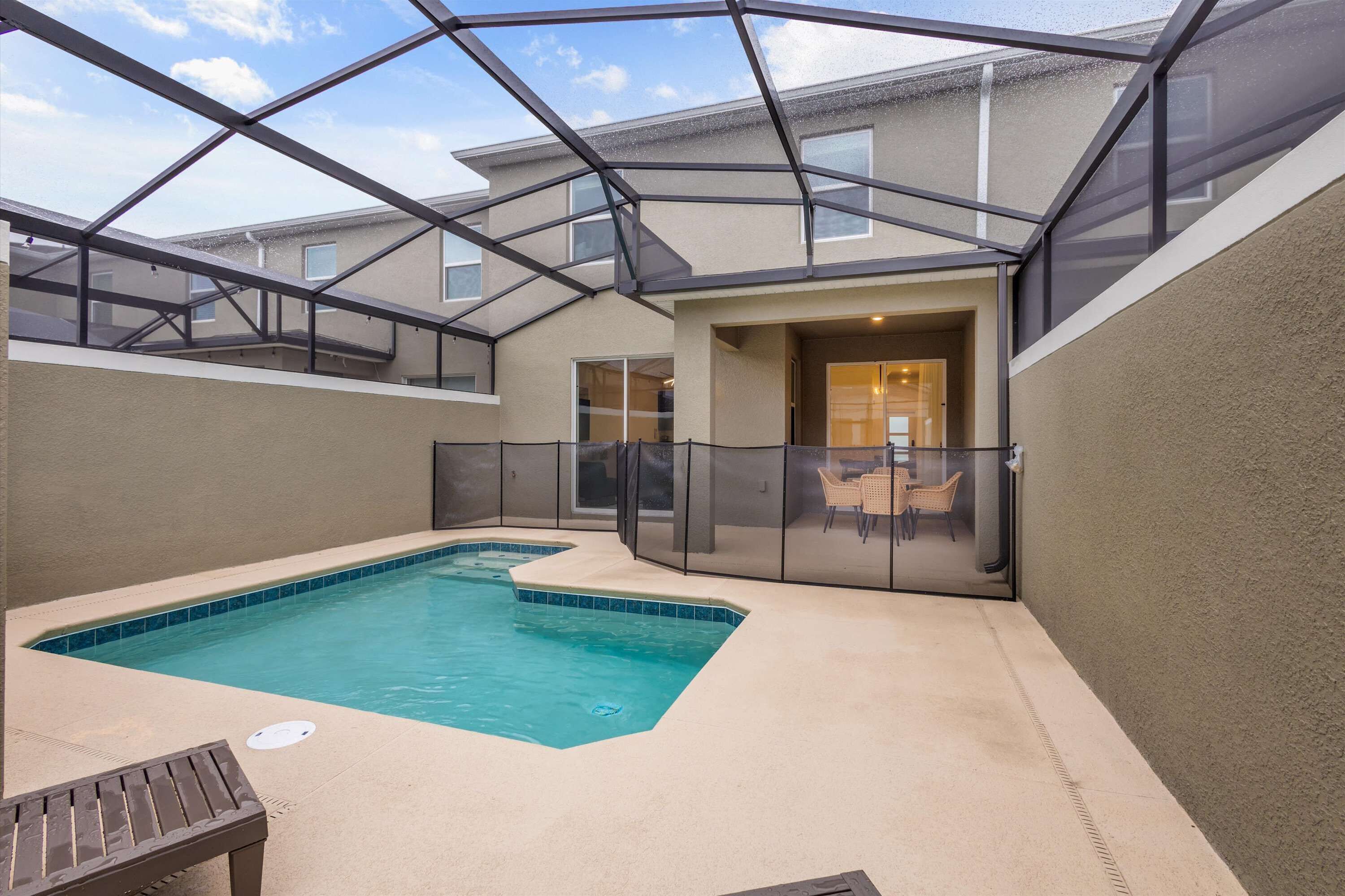 Una piscina con cerramiento de cristal, una silla de descanso y una zona de terraza.