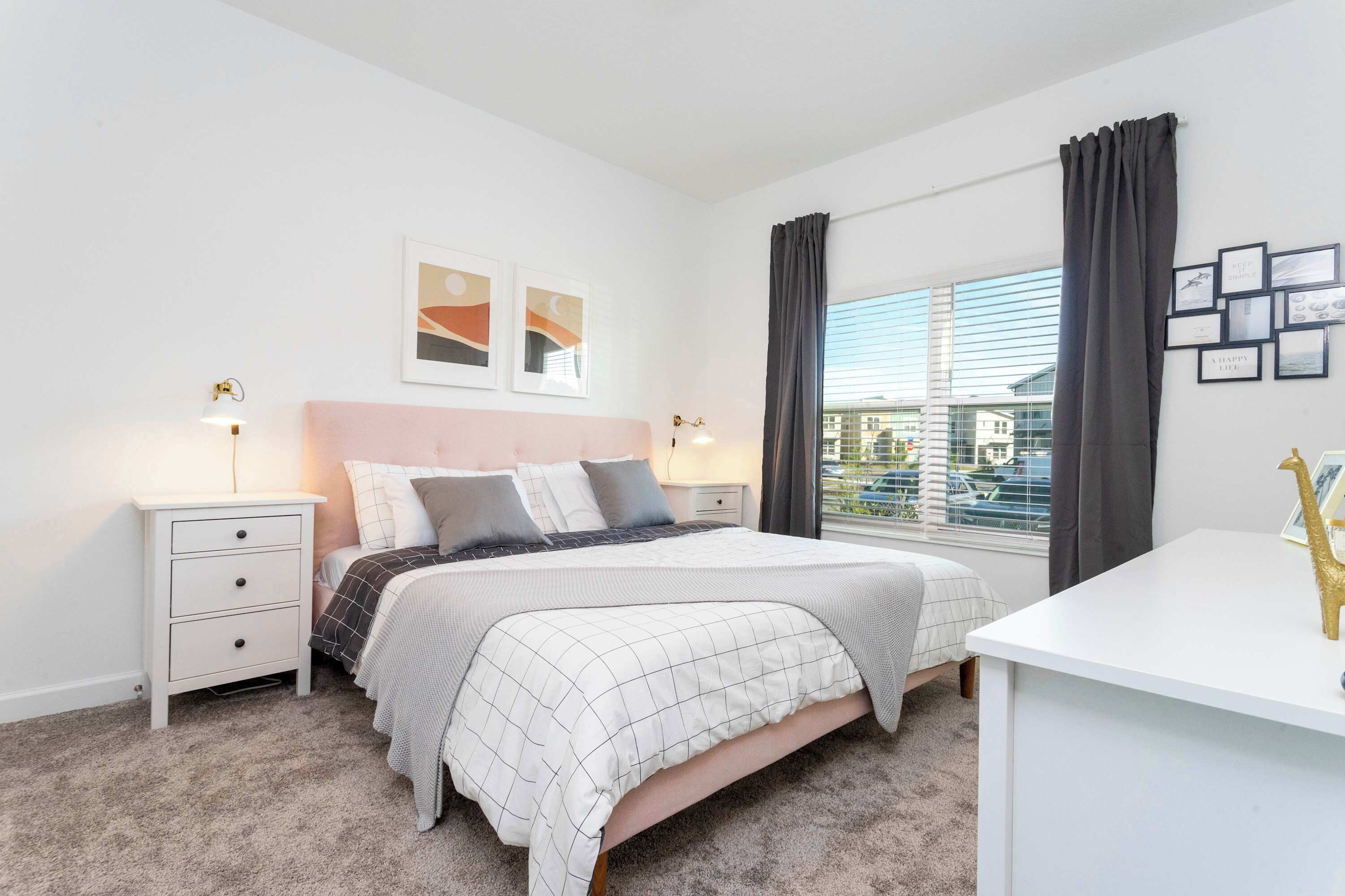 A bedroom with a bed, bedside tables, a desk, and a window with curtains.
