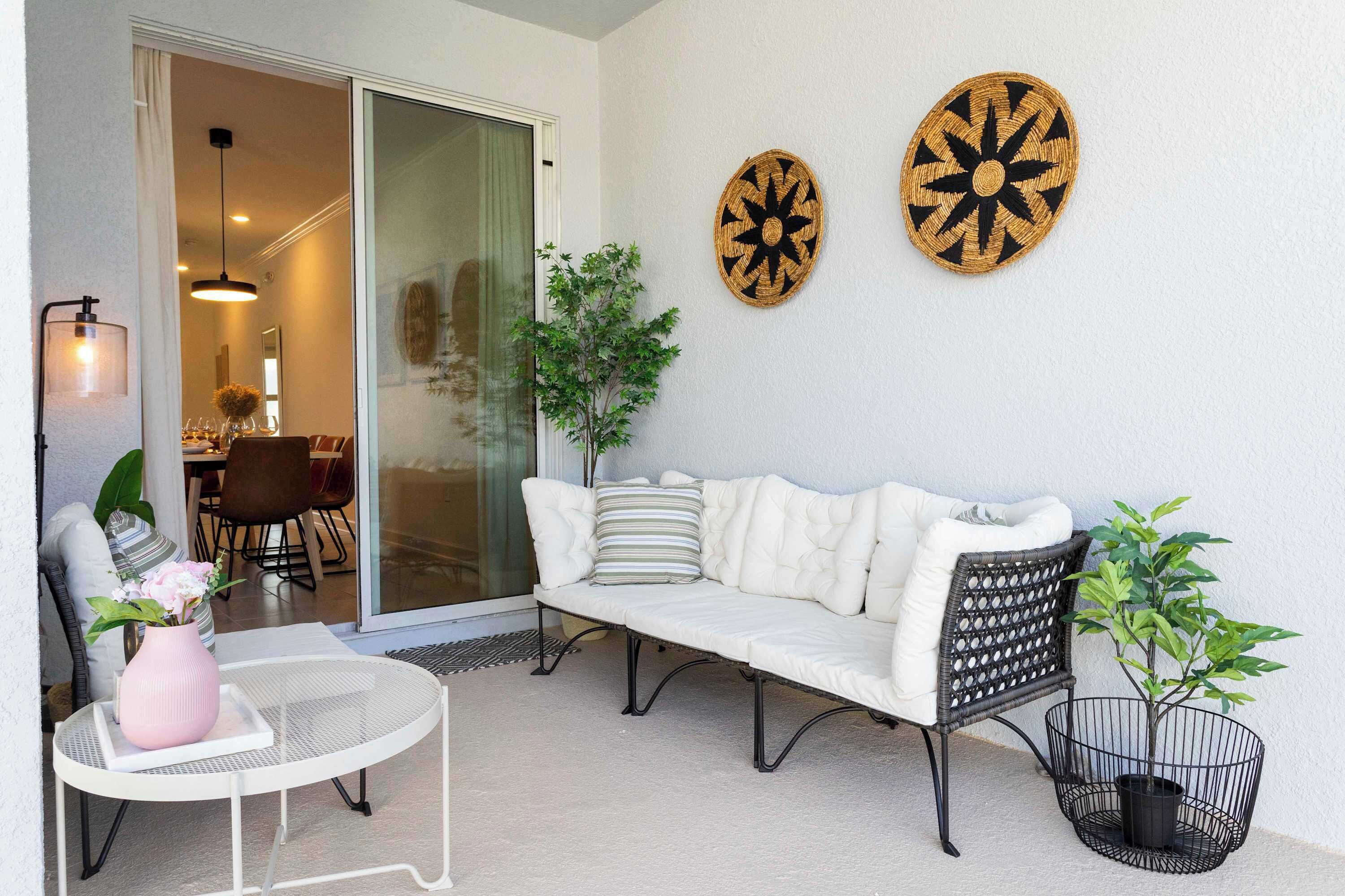 A cozy outdoor seating area with a white sofa, a round table, and a potted plant.