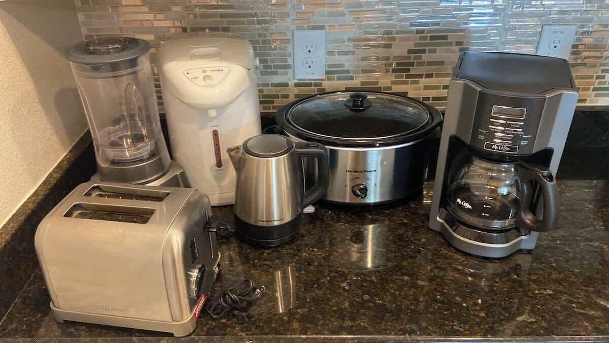 Eine Küchenarbeitsplatte mit Toaster, Kaffeemaschine, Slow Cooker, Wasserkocher und Mixer.