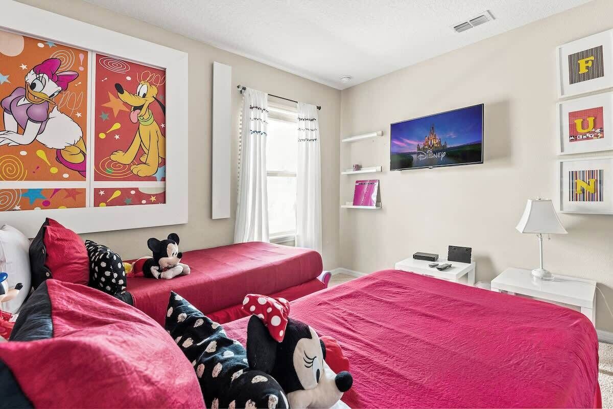 Ein Hotelzimmer mit zwei Betten, einem Fernseher und Disney-Dekorationen.
