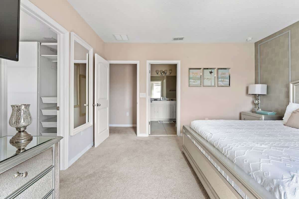 A bedroom with a bed, a dresser, a vanity, and a closet.