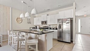 A modern kitchen with white cabinetry, stainless steel appliances, and pendant lighting. - Themed Mickey Bedroom 4BR at Solterra (Davenport)