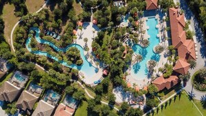 An aerial view of a resort with multiple swimming pools, a winding water slide, and surrounding greenery. - Themed Mickey Bedroom 4BR at Solterra (Davenport)