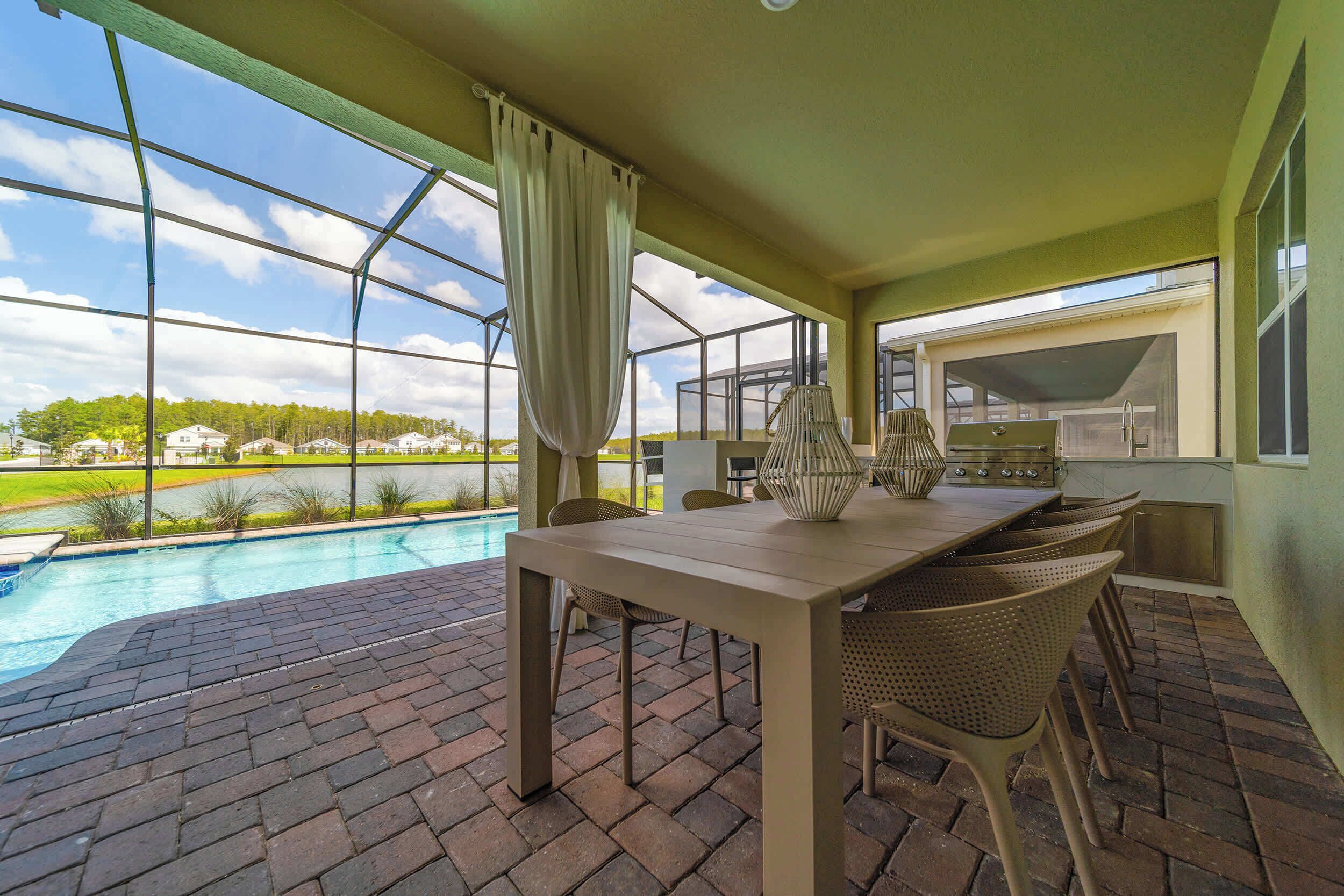 Un patio couvert avec une piscine, un espace repas extérieur et une vue sur un quartier résidentiel.