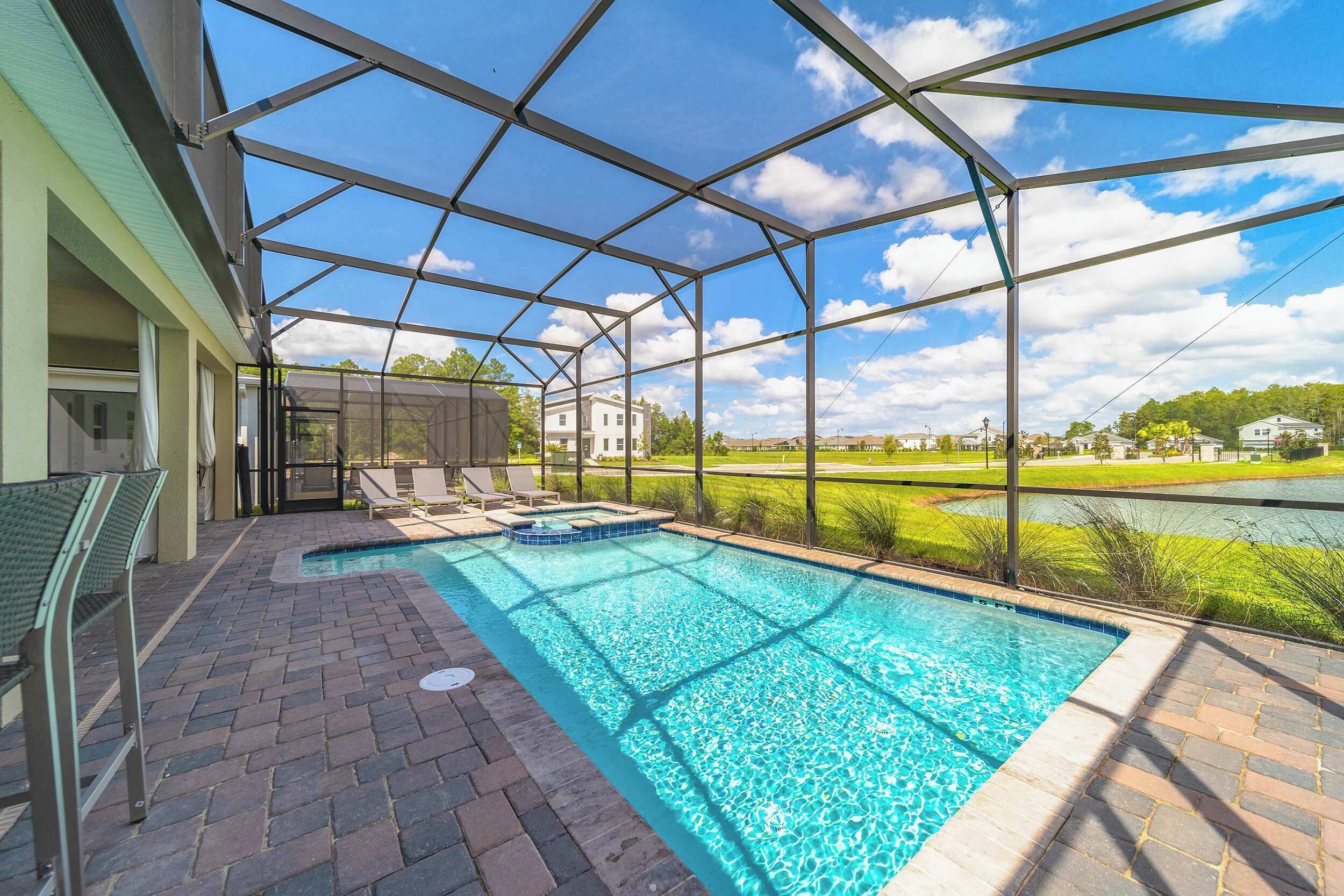 A covered outdoor swimming pool with a view of a lake and buildings in the background.