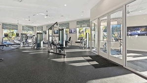 Uma academia moderna com diversos equipamentos de exercício, janelas amplas e um interior limpo e bem iluminado.