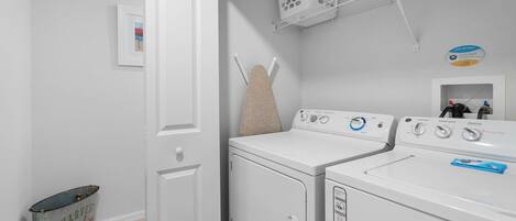 A laundry area with a washing machine, dryer, and a hanging laundry basket.