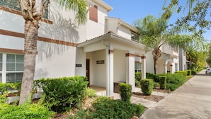 A row of modern residential buildings with a covered porch, a clear sky, and well-maintained landscaping. - Townhome 4BR With Pool at Storey Lake (Kissimmee)
