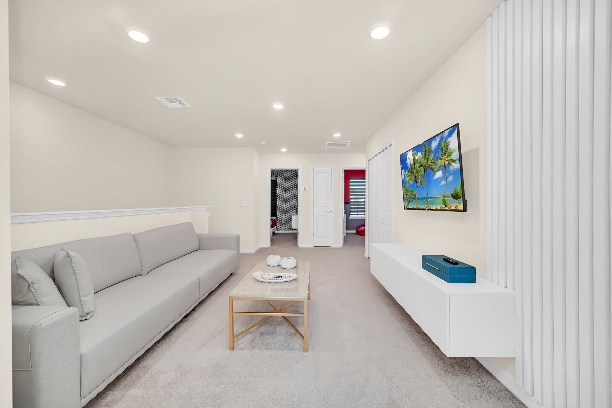 Ein modernes Wohnzimmer mit einer Couch, einem Couchtisch und einem an der Wand befestigten Fernseher.