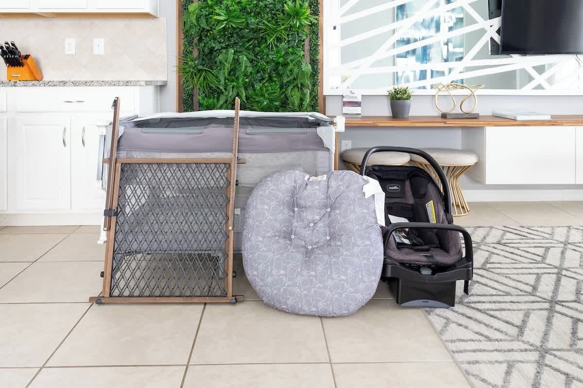 A compact living space with a bed, a pet gate, and a baby stroller.