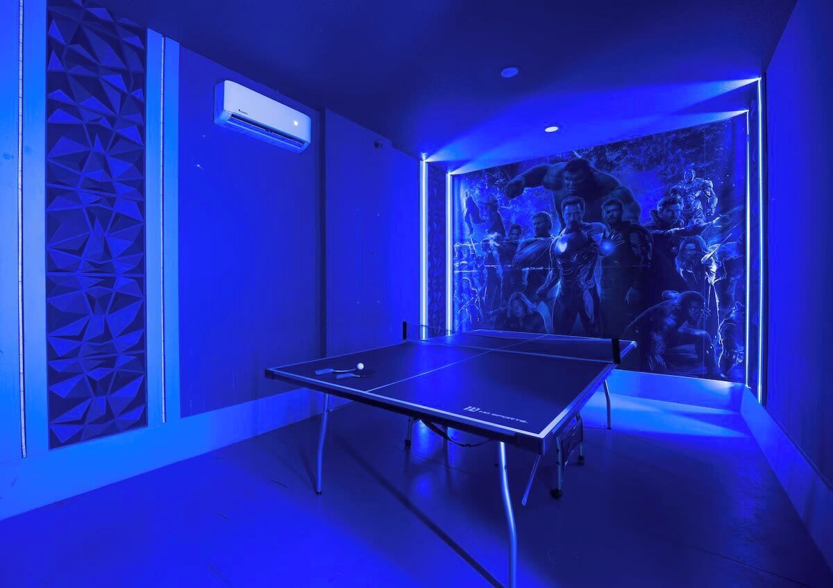 A room with a ping pong table, a geometric wall pattern, and a large poster of a movie scene.