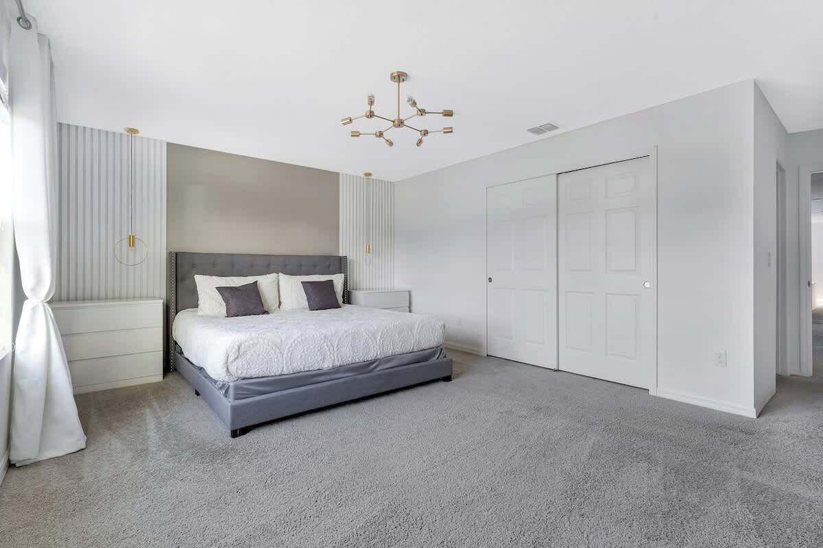 A bedroom with a bed, a wardrobe, and a chandelier.