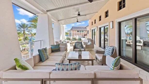 A covered outdoor seating area with a sofa, chairs, and a table. - Stunning 7BR Home With Themed Bedrooms (Kissimmee)