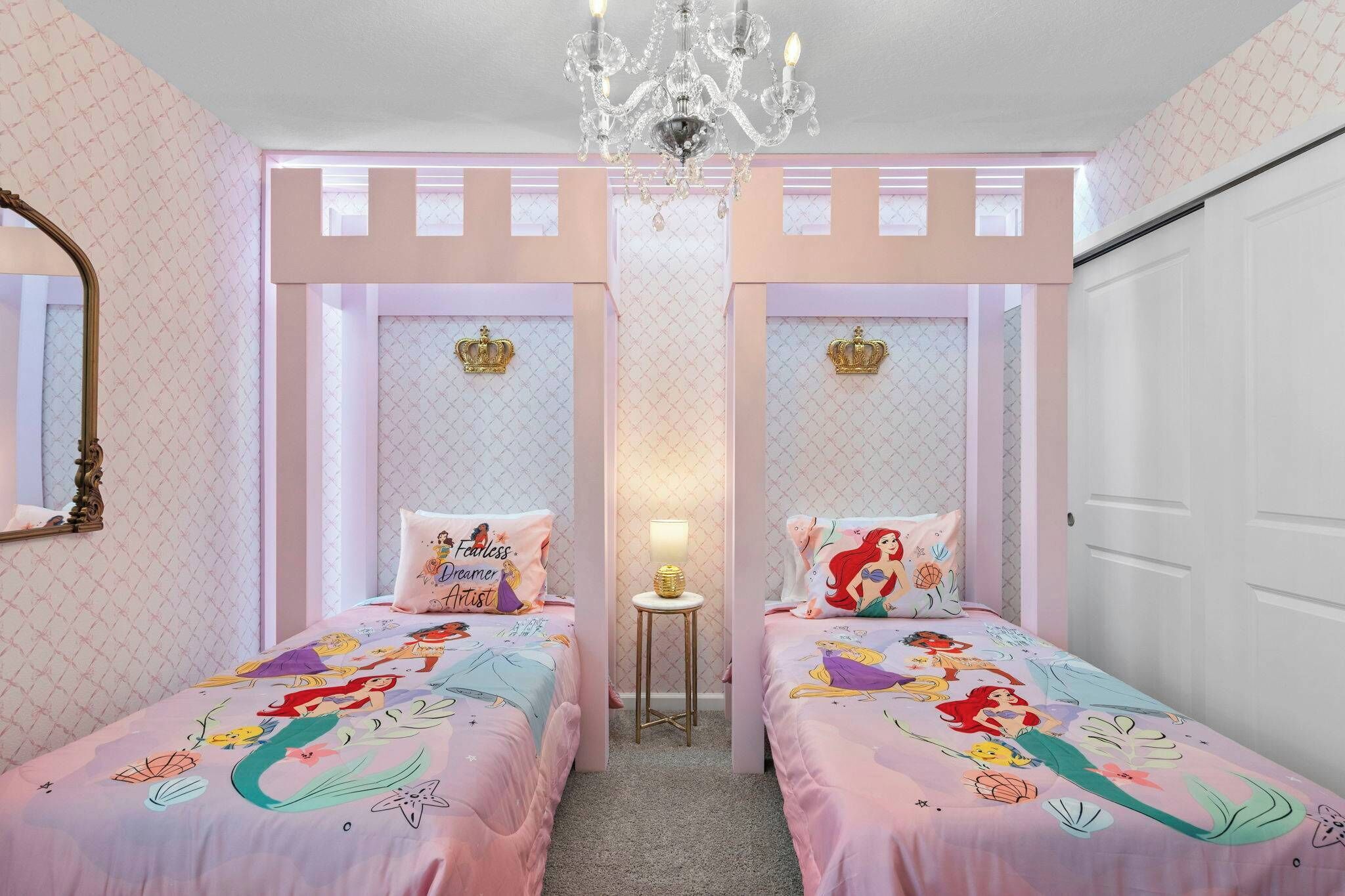 Une chambre avec deux lits, un lustre, un miroir et une porte.