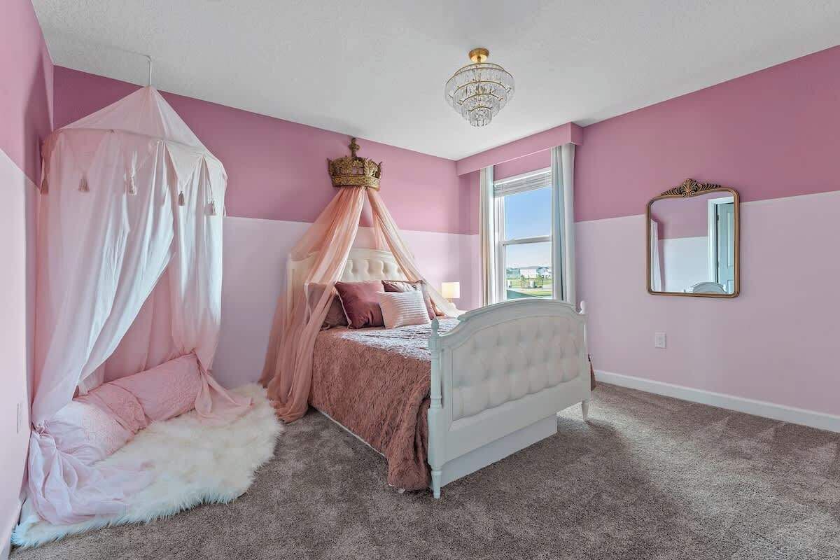 A bedroom with a canopy bed, a large window, and a chandelier.