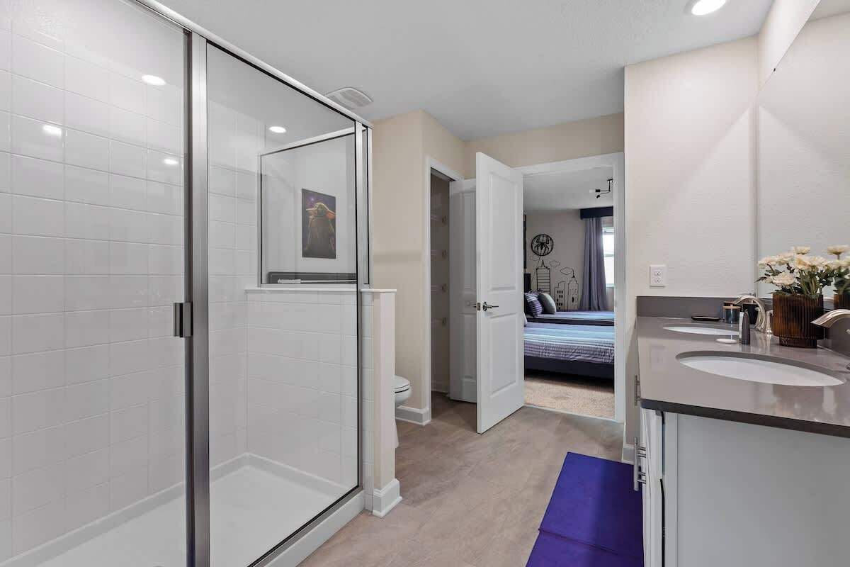 A modern bathroom with a glass shower enclosure, a toilet, and a sink with a mirror.