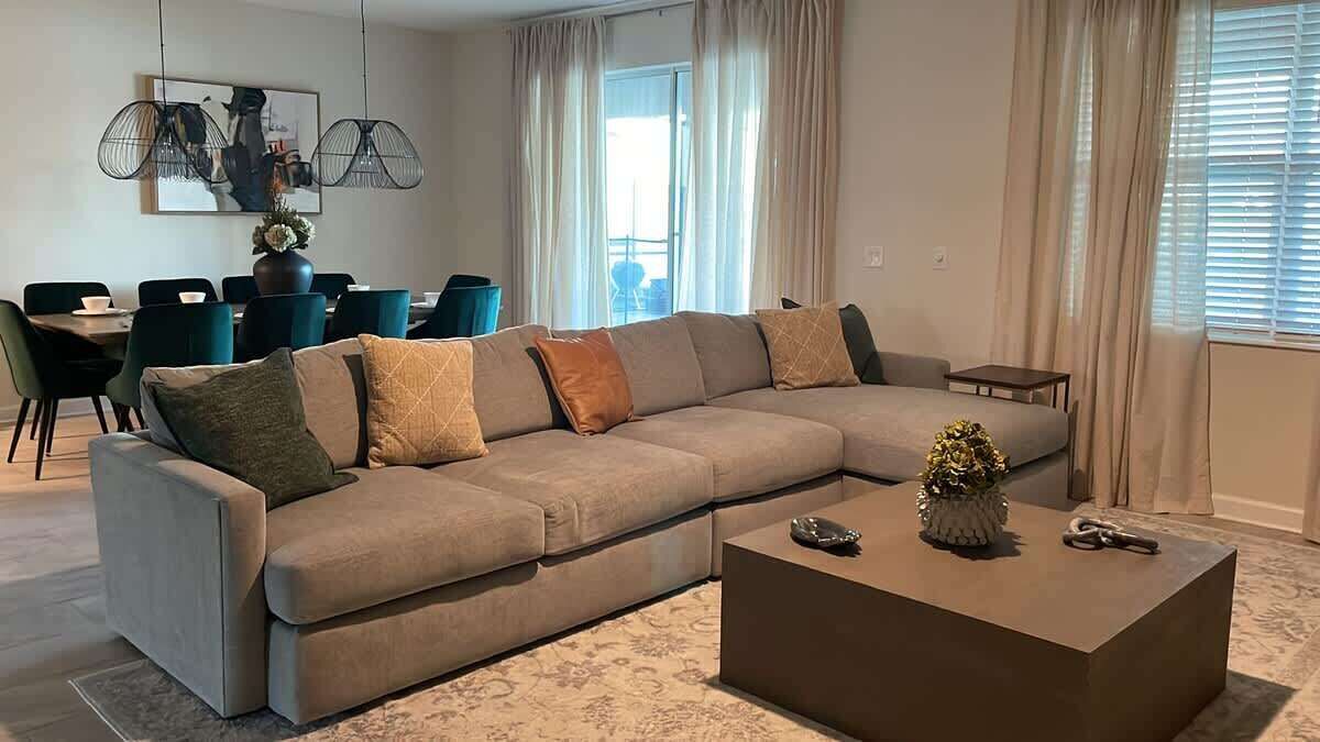 A modern living room with a sectional sofa, a coffee table, and a dining area with chairs and a table.