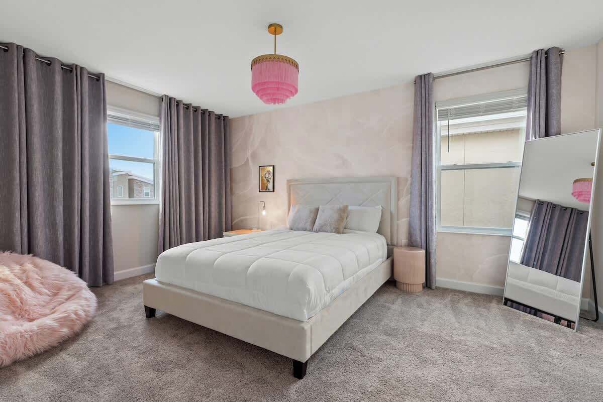 Ein Schlafzimmer mit einem Bett, einem großen Spiegel und einem flauschigen Teppich.