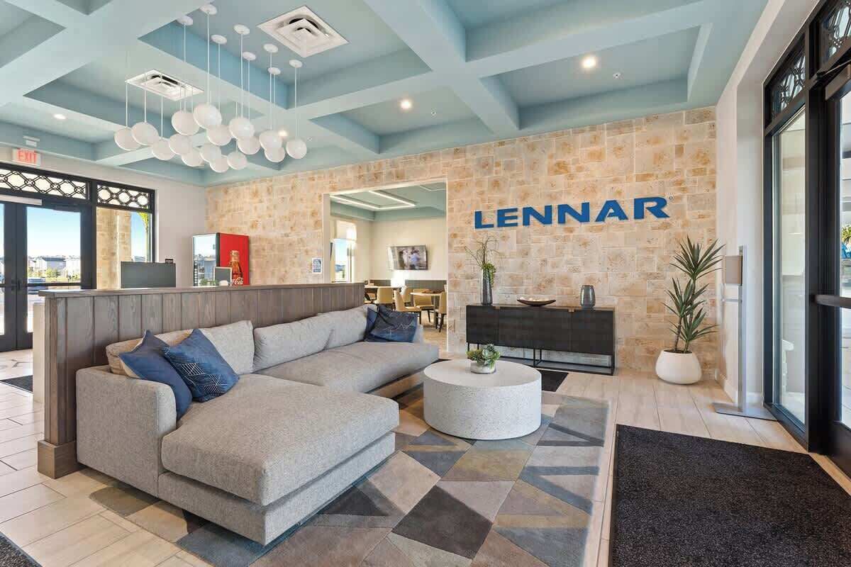 A modern lobby with a large LENNAR sign, a sectional sofa, a round coffee table, and a stone accent wall.