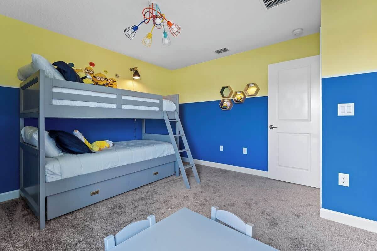 Een kinderkamer met stapelbedden, een bureau en een deur.