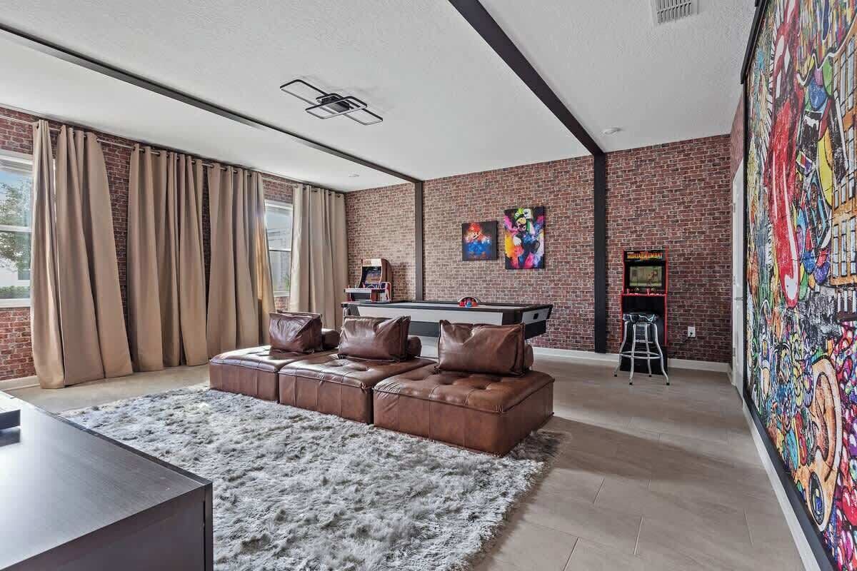 A modern living room with a sectional sofa, a pool table, and a vibrant mural.