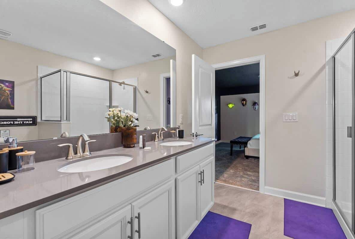 A modern bathroom with two sinks, a large mirror, and a vanity cabinet.