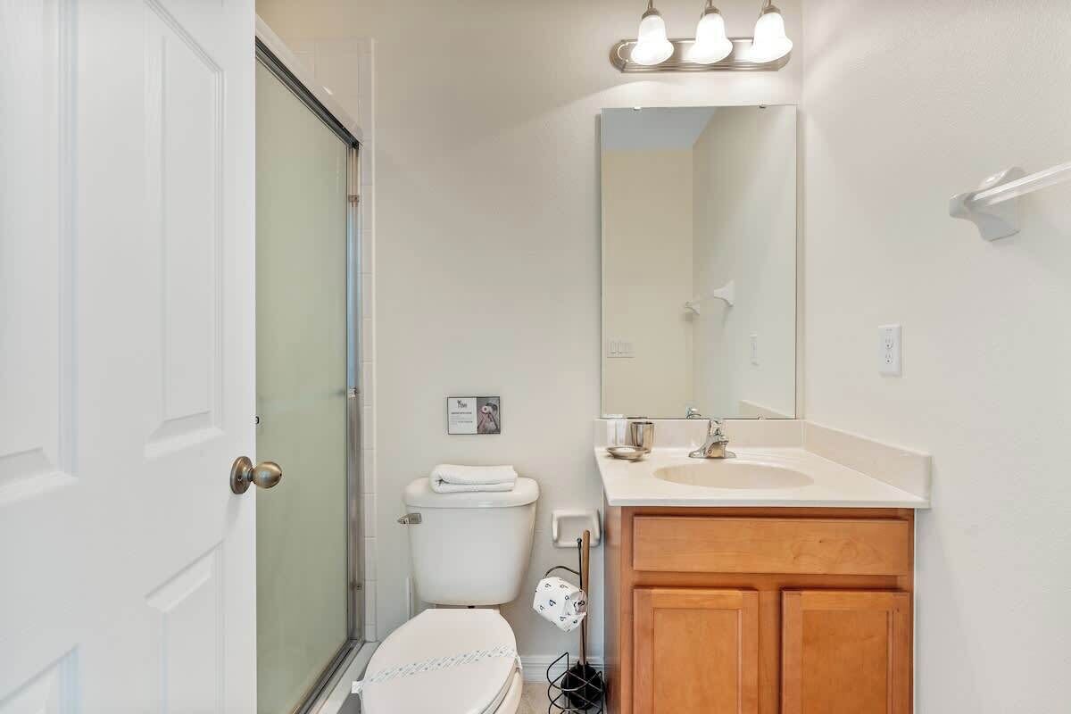 Une salle de bain comprenant des toilettes, un lavabo, un miroir et une douche.