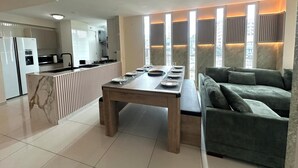 A modern kitchen with a built-in island, a dining area with a wooden table and chairs, and a green sofa in a living area with large windows and city views. - Fabulous 5-bedroom apartment with AC in vibrant Panamá (Panamá)