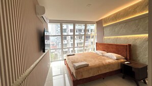 A modern bedroom with a large bed, a TV mounted on the wall, and a view of the city through large windows. - Fabulous 5-bedroom apartment with AC in vibrant Panamá (Panamá)