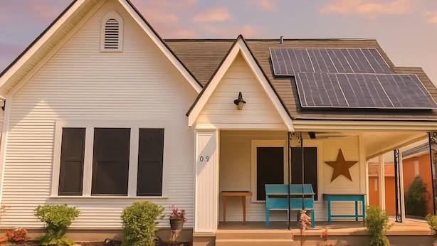 Einbungalow mit einer Veranda, einem Solarpaneel auf dem Dach und einer Stern-Dekoration an der Wand.