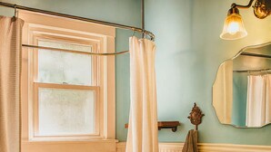 Ein Badezimmer mit Badewanne, Waschbecken, Fenster und Spiegel.