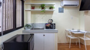 Een kleine keuken met een magnetron, spoelbak en potplanten.