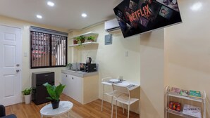 Een compact woongedeelte met een kitchenette, een eethoek en een tv waarop 'NETFLIX' wordt afgespeeld.