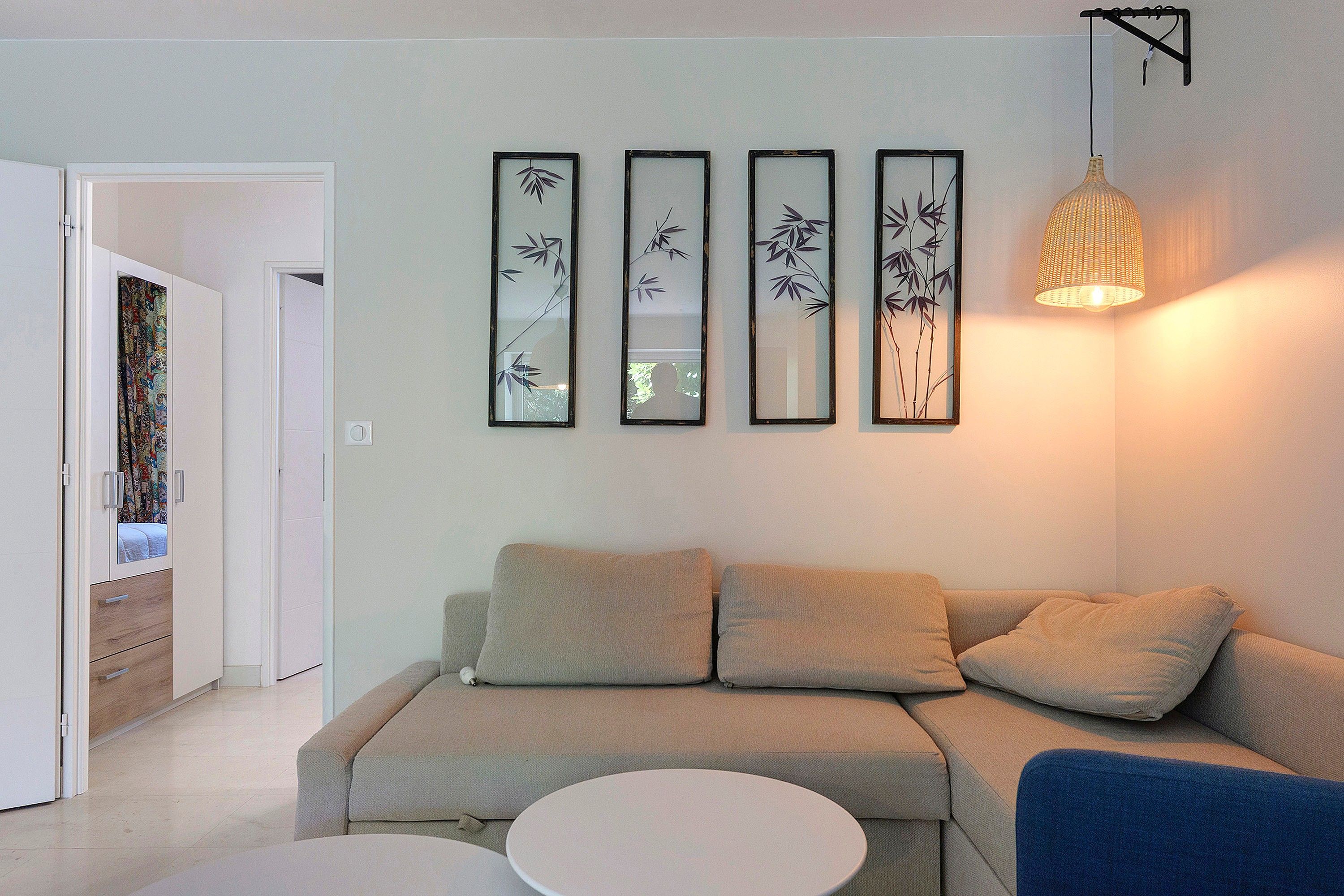 Uma sala de estar com um sofá, uma mesa de centro redonda e um lustre.