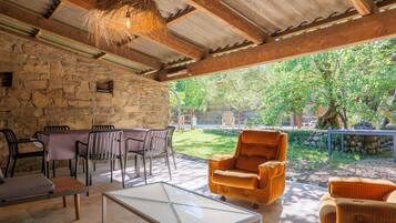 An outdoor patio with stone walls, a table with chairs, and a hanging light fixture.