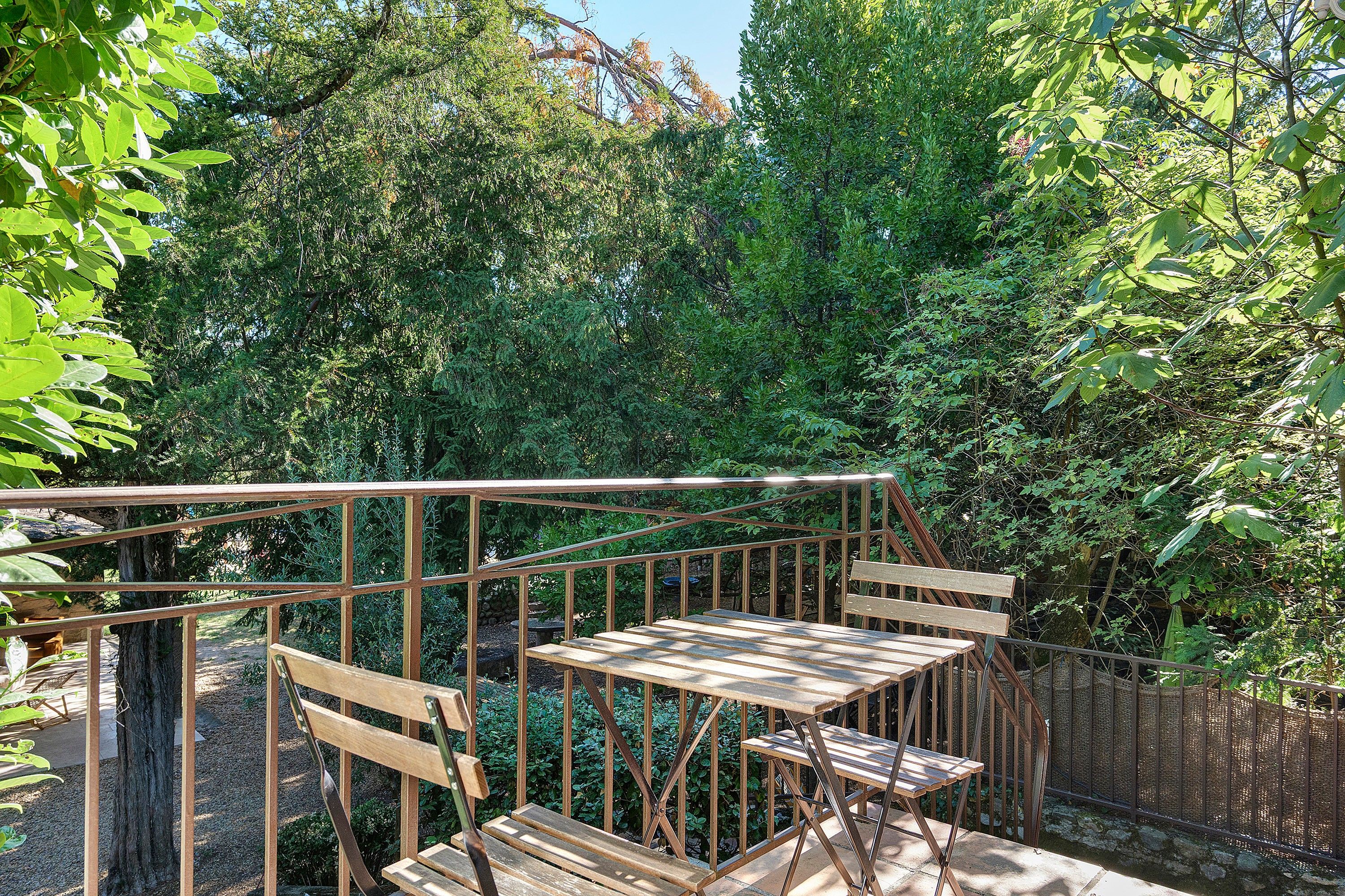 A wooden deck with a metal railing, surrounded by dense foliage.