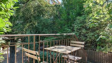 A wooden deck with a metal railing, surrounded by dense foliage.